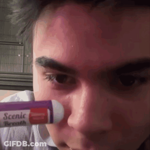 A Close Up Of A Person 'S Face With A Tube Of Scenic Breath GIF