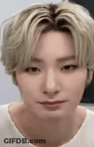 A Close Up Of A Person 'S Face With Blonde Hair And A White Shirt On . GIF