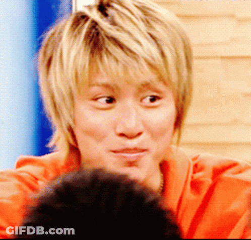 A Close Up Of A Person 'S Face With Blonde Hair And An Orange Shirt GIF