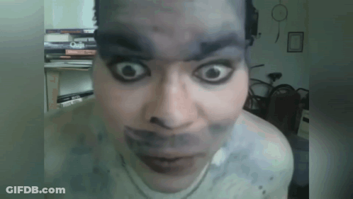 A Close Up Of A Person 'S Face With Books On The Shelf Behind Them GIF