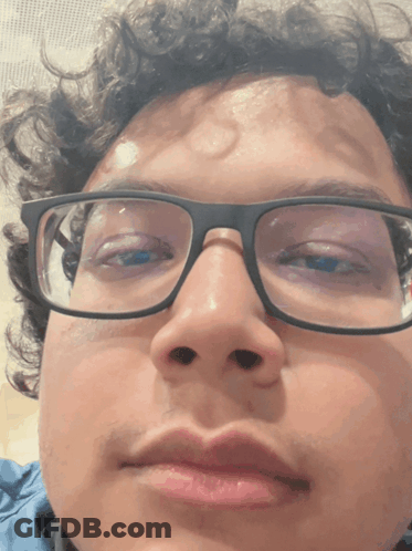 A Close Up Of A Person 'S Face With Glasses And Curly Hair GIF