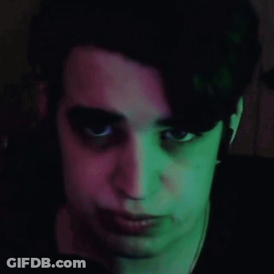 A Close Up Of A Person 'S Face With Green And Pink Lights Behind Them GIF