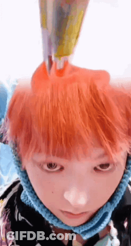 A Close Up Of A Person 'S Face With Orange Hair And A Blue Scarf Around Their Neck GIF