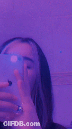 A Close Up Of A Person 'S Face With Purple Lights Behind Her GIF