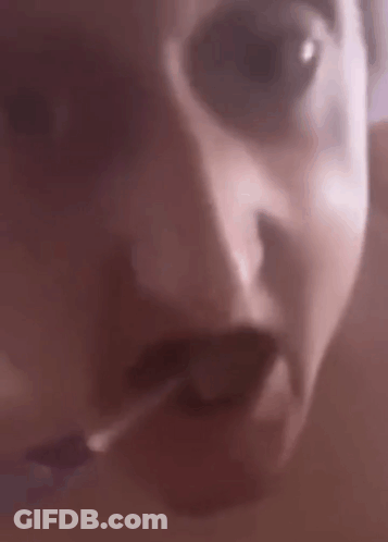 A Close Up Of A Person 'S Face With Their Mouth Open And A Cigarette In Their Mouth . GIF
