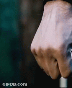 A Close Up Of A Person 'S Fist Holding A Cane In A Dark Room . GIF