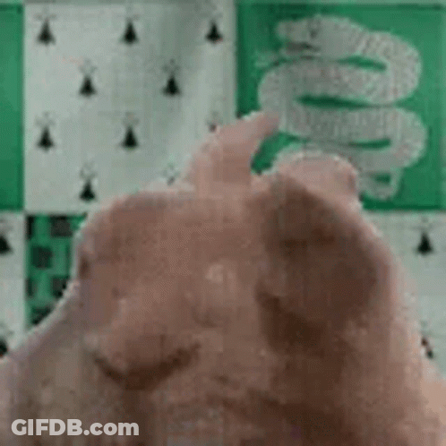 A Close Up Of A Person 'S Hand Giving A Thumbs Up In Front Of A Green And White Checkered Wall . GIF