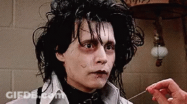 A Close Up Of A Person 'S Hand Holding A Needle To A Man 'S Face . GIF