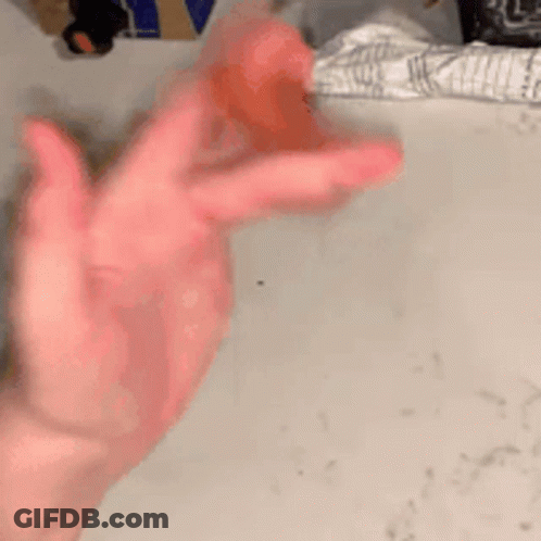 A Close Up Of A Person 'S Hand Holding A Red Object On A Table . GIF