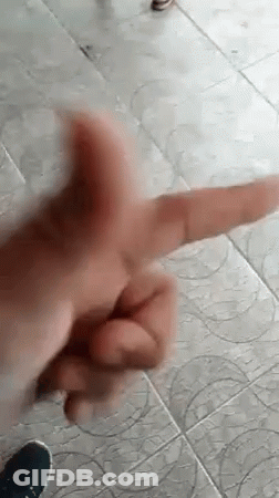A Close Up Of A Person 'S Hand Making A Peace Sign On A Tile Floor . GIF