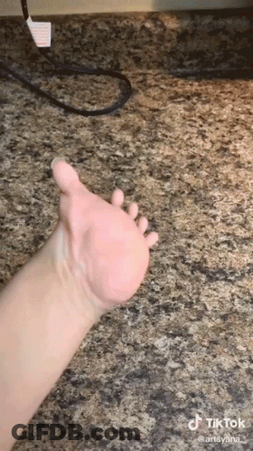 A Close Up Of A Person 'S Hand On A Granite Countertop . GIF