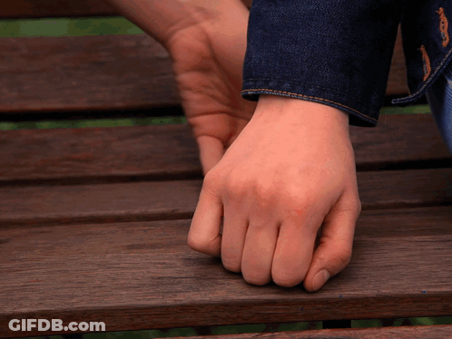 A Close Up Of A Person 'S Hand On A Wooden Bench GIF