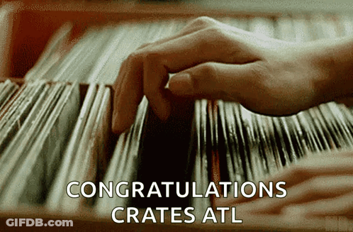 A Close Up Of A Person 'S Hand Picking A Record From A Shelf That Says Congratulations Crates GIF