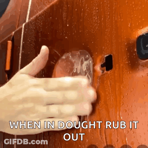 A Close Up Of A Person 'S Hand Rubbing A Glass With The Words When In Dough Rub It Out Below It GIF