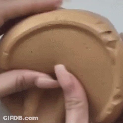 A Close Up Of A Person 'S Hands Holding A Brown Container . GIF