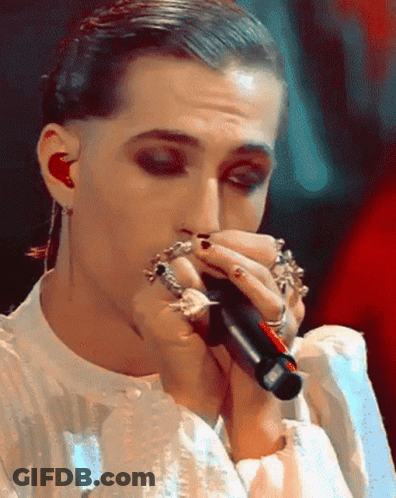 A Close Up Of A Person Singing Into A Microphone With Rings On Their Fingers GIF