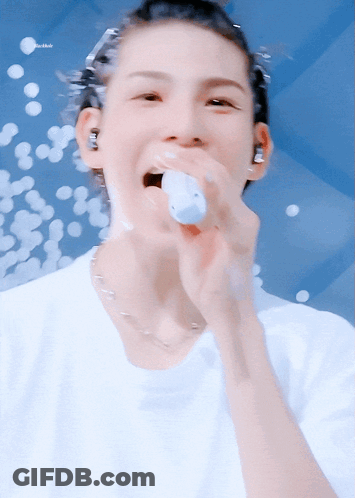 A Close Up Of A Person Singing Into A Microphone With The Word Bubbles In The Background GIF