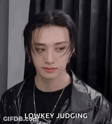 A Close Up Of A Person Wearing A Black Jacket And A Black Necklace . GIF