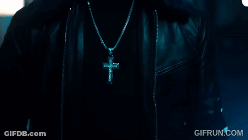 A Close Up Of A Person Wearing A Cross Necklace With Gifrun.com In The Corner GIF