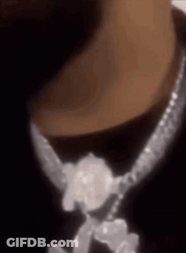 A Close Up Of A Person Wearing A Necklace With Diamonds On It GIF