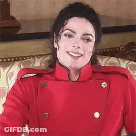 A Close Up Of A Person Wearing A Red Jacket And Smiling While Sitting On A Couch . GIF