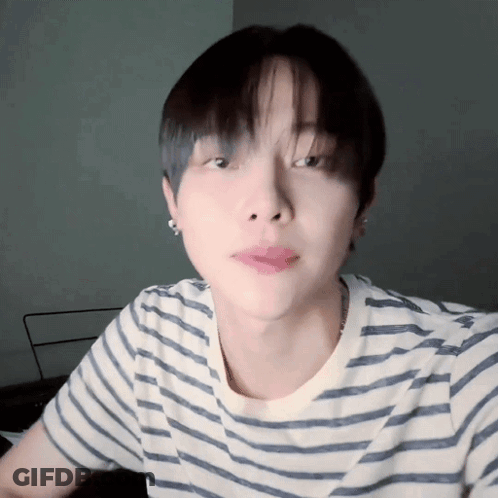 A Close Up Of A Person Wearing A Striped Shirt And Earrings GIF