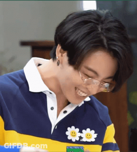 A Close Up Of A Person Wearing Glasses And A Sweater With A Smiley Face On It . GIF