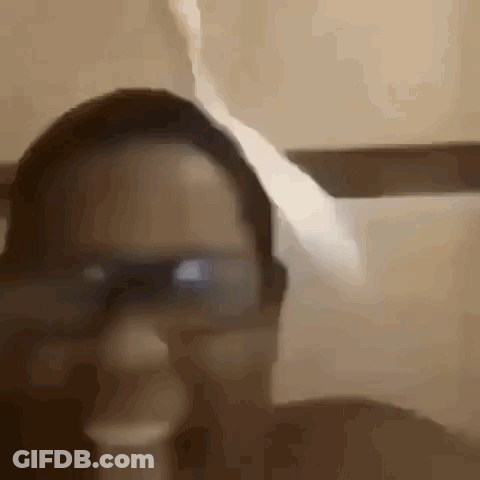 A Close Up Of A Person Wearing Glasses And Smoking A Cigarette In A Bathroom . GIF