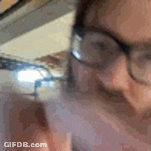 A Close Up Of A Person Wearing Glasses Talking On A Phone . GIF