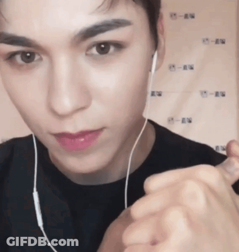 A Close Up Of A Person Wearing Headphones And Making A Heart Shape With Their Hands GIF