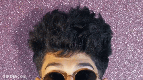 A Close Up Of A Person Wearing Sunglasses And A Purple Background GIF