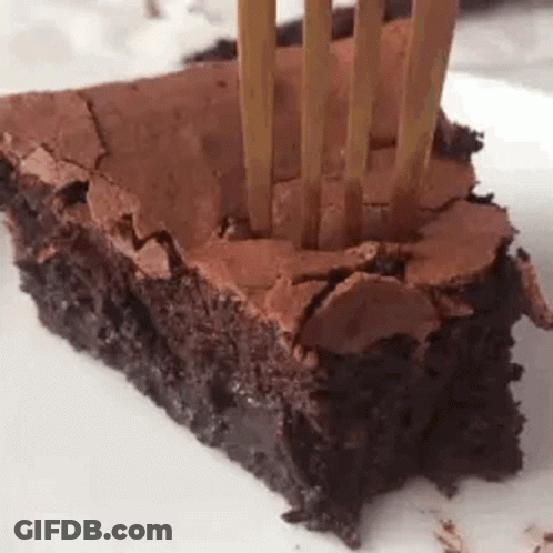 A Close Up Of A Piece Of Chocolate Brownie With A Fork Sticking Out Of It . GIF
