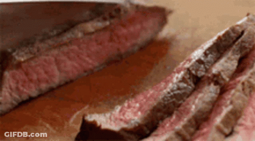 A Close Up Of A Piece Of Steak Being Sliced On A Cutting Board . GIF