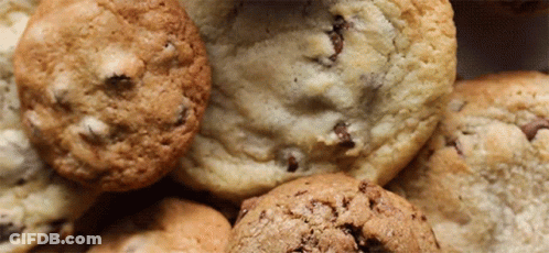 A Close Up Of A Pile Of Cookies Including Chocolate Chip Cookies GIF