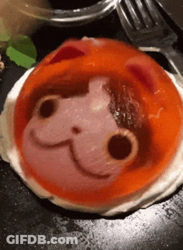 A Close Up Of A Plate Of Food With A Cat Face Drawn On It GIF