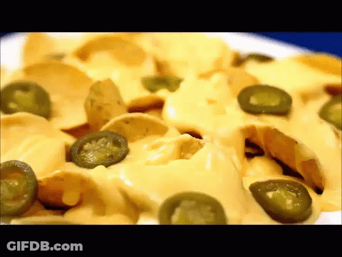 A Close Up Of A Plate Of Nachos With Jalapenos And Cheese GIF