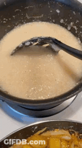 A Close Up Of A Pot Of Soup With A Spoon In It On A Stove . GIF