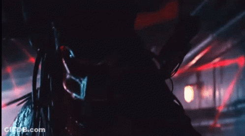 A Close Up Of A Predator In A Dark Room With Red Lights GIF