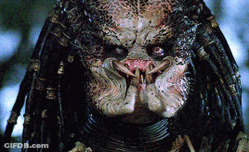 A Close Up Of A Predator 'S Face With Dreadlocks And Sharp Teeth GIF