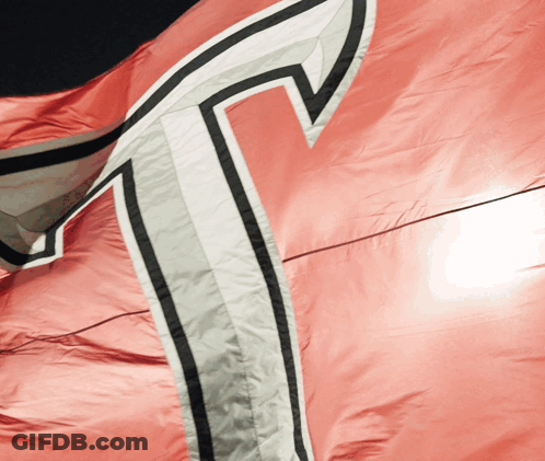 A Close Up Of A Red Flag With A White T On It GIF