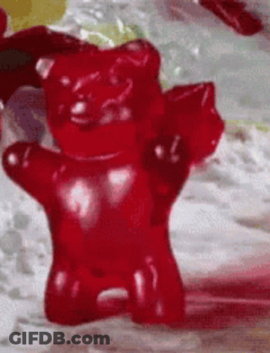 A Close Up Of A Red Gummy Bear On A Table GIF