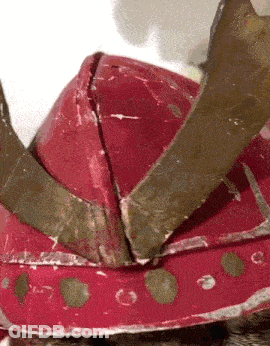 A Close Up Of A Red Helmet With A Crown On It GIF