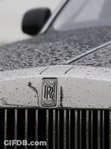 A Close Up Of A Rolls Royce Car With Rain Drops On It GIF