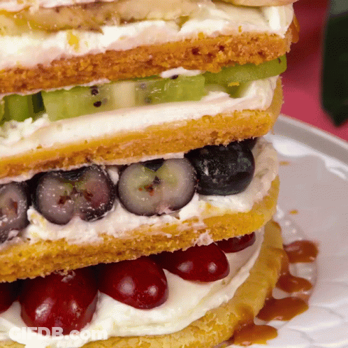 A Close Up Of A Sandwich With Blueberries And Cherries On A Plate GIF