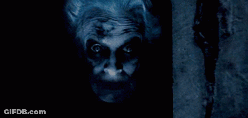 A Close Up Of A Scary Clown 'S Face With A Dark Background GIF