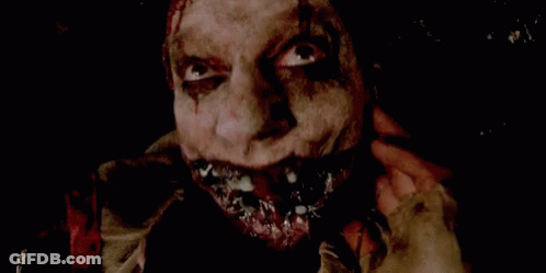 A Close Up Of A Scary Clown 'S Face With Blood Coming Out Of His Mouth . GIF