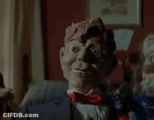 A Close Up Of A Scary Puppet In A Suit And Bow Tie . GIF