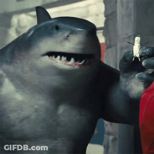 A Close Up Of A Shark Holding A Small Figure In Its Mouth GIF