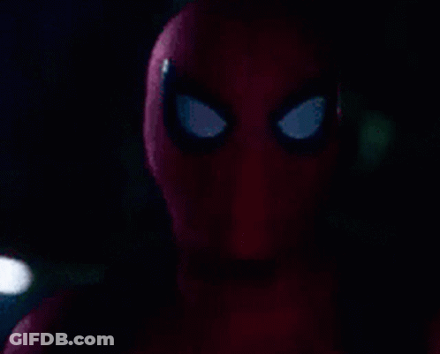 A Close Up Of A Spider-Man 'S Face With A Flashlight In The Background . GIF