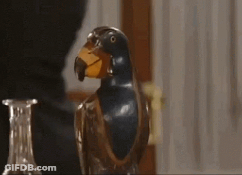 A Close Up Of A Statue Of A Parrot With A Yellow Beak On A Table . GIF